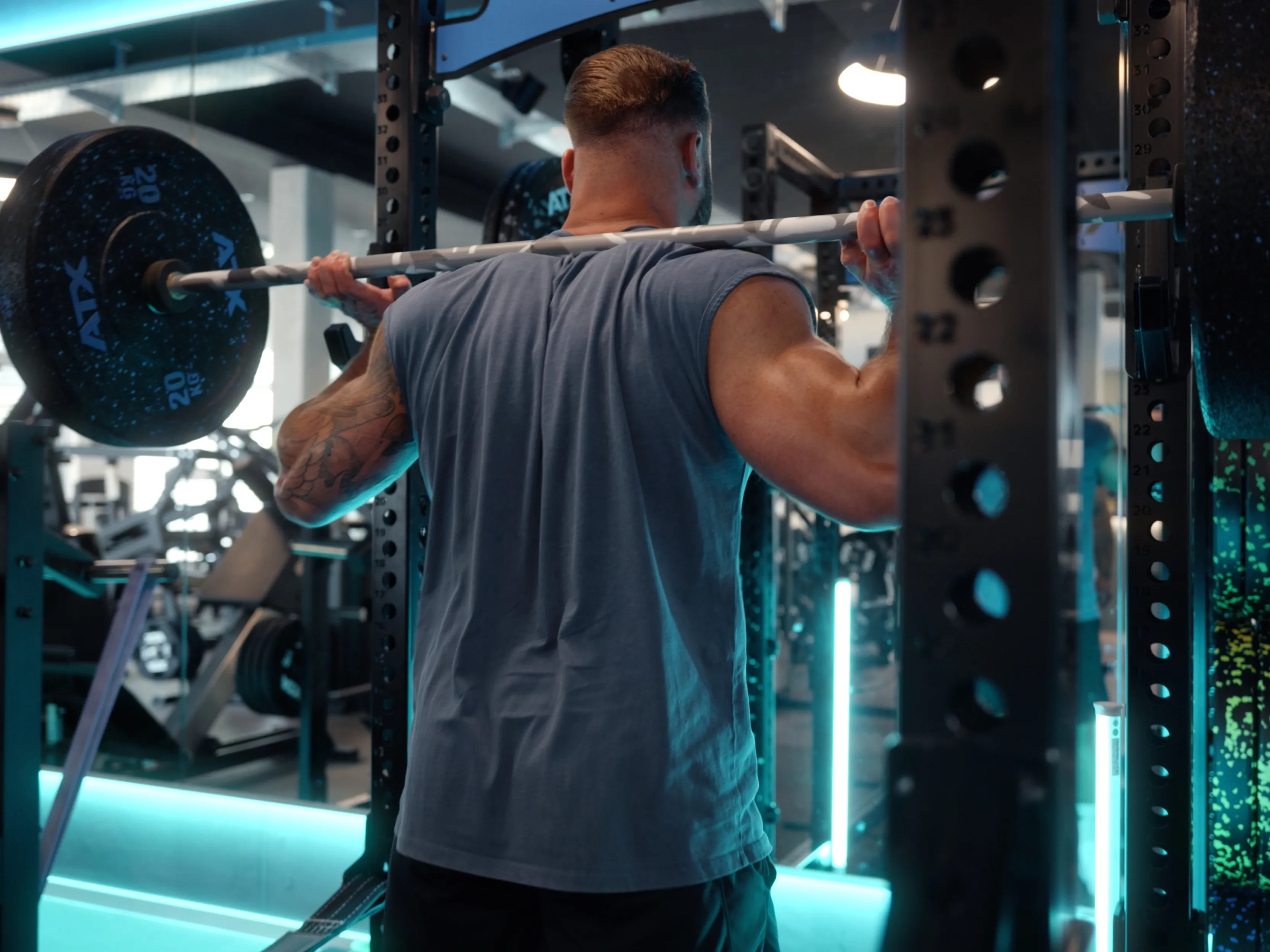 Mann mit Muskelarm hebt Langhantel mit Gewichten im Fitnessstudio.